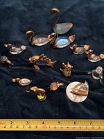 Full assortment of 14 crystal and metal miniature animal and sailboat figurines displayed on dark fabric background with measuring tape for scale.