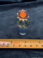 Full view of the Swarovski crystal sunflower in its blue pot with a measurement tape showing approximately 2 inches tall.