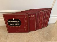 Front view of 6 red slipcases of Philharmonic Family Library of Great Music records displaying the front title and decorative detailing.