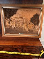 Front view of framed wood carving showing family in horse-drawn wagon by covered bridge