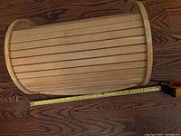 Top-down view of the wooden breadbox showing the roll-top slatted lid and its size in relation to a measuring tape.