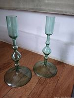 Pair of green glass candlestick holders with rounded wide bases and decorative stems
