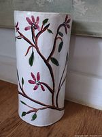 Side view of the hand-made stoneware vase showing floral painted design in pink, green, and brown on white background.