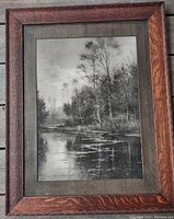 Full view of the framed sepia river landscape print showing oak frame and mat.