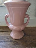 Full view of pink vintage Abingdon ceramic vase with double handles on wooden surface against window light.