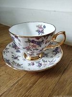 Teacup and saucer set photographed from side angle showing floral pattern and gold trim