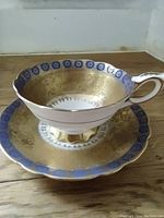 Front angle view showing the detailed blue and gold patterns inside the teacup and on the matching saucer.