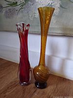 Photo of two colored glass bud vases, one amber and the other red with a ruffled top.