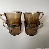 Four amber/brown glass mugs stacked in pairs showing size, shape, and color.