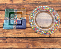 Round and square colorful art glass plates displayed on wooden surface showing design and relative size.