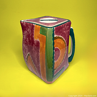 Front corner view showing the colourful geometric pattern and the handle on the side.