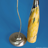 Close-up of a pendant light showing satin nickel ceiling mount base and yellow blaze elongated glass shade with multi-color streaks.