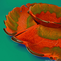 Close-up of the orange and olive green leaf-shaped dishes, showing the bronze edged details and speckled glaze