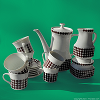 Full set of tea items including stacked cups, saucers, teapot, creamer, and sugar bowl on a green background.