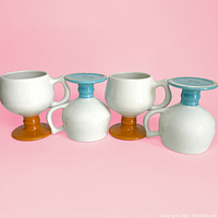 All four mugs shown upright and upside down, displaying orange and blue pedestal bases