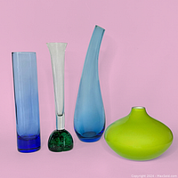 Photo showing four distinct glass vases on a pink background: blue cylinder, clear tulip with green base, curved blue tear drop, and short lime green bulbous vase.