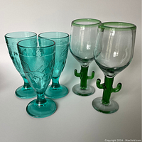 Photo showing five glasses including two clear glasses with green cactus-shaped stems and three turquoise embossed pattern glasses.