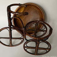 Top view of the rattan bike planter showing the three rounded wheels and handlebar details, illustrating the craftsmanship and wear.