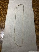 Full view of the 14 inch gold chain on a fabric background.