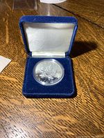 Silver coin with Canadian maple leaf design rated .9999 fine silver, shown in blue velvet case.