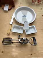 Overview of the lot showing the pie plate, carving tool, milk glass soap dishes, and hand beater.