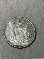 Reverse side of the 1966 Canadian fifty cent coin showing the Canadian coat of arms with date and denomination.