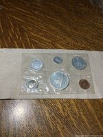 Photo showing the sealed coin set with all 6 coins visible against a white background on a wooden surface.
