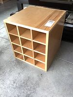 Wooden veneer cubby with 12 slots, side angled view showing depth and construction. Placed on concrete floor.