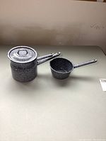 Full view of the double boiler set with lid and small pot, showing speckled enamel coating and handles.