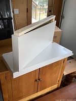 Photo showing the two white floating shelves stacked with visible wooden mounting brackets for attachment.