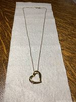 Full view of the heart necklace showing the entire chain and pendant on a white cloth surface.