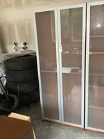 Front view of the large IKEA bookcase with frosted glass doors closed, showing its height and door style.