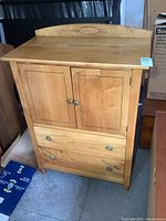 Front view of maple dresser showing two cabinet doors and two drawers with metal pulls, carved back panel detail.