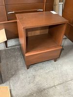 Front and side angle of the vintage Mid-Century Modern nightstand showing drawer and open shelf on bottom and middle sections, highlighting minor wear.