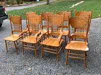 Eight oak dining chairs arranged outdoors on gravel showing full set