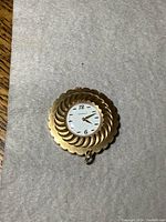Top view of gold-tone Caravelle windup pendant watch with white face and gold hands.