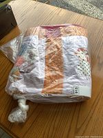 Quilt folded and wrapped in plastic, showing its thickness and colors.