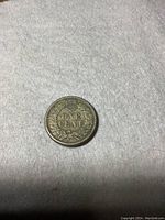 Reverse side of the 1863 Indian Head one cent coin showing 'ONE CENT' with laurel wreath and shield.