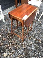 Side view of the vintage solid wood drop leaf side table showing one leaf lowered and the turned leg details.