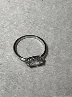 Image of the sterling silver solitaire ring showing the marquise-cut clear center stone and halo setting.