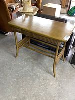 Top and front view showing vintage wood table with smooth rectangular wooden surface and rounded edges, placed on a concrete floor.
