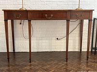 Front view showing three drawer front, brass bail handles and rosewood inlay edge