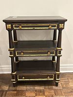 Front view of the dark brown bookshelf with gold trim and three drawers, showing slight surface scratches.