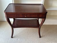 Front view of the cherry wood side table showing drawer and lower shelf