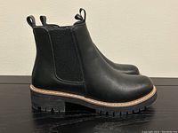 Side view of the black Aqua Diva boots showing elastic panel and chunky lug sole.