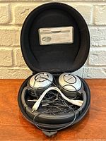 Headphones inside open case showing earcups, coiled cable and documentation card in lid.