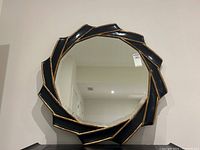 Front view of the round mirror showing full black and gold twisted frame and reflective glass.