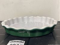 Side angle showing green exterior with white glazed interior and crimped scalloped edge.