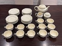 Full set arranged on table showing all cups, saucers, plates, teapot, creamer, sugar pot and basket