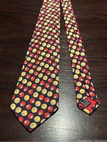 Full view of the Gucci necktie laid flat on a wooden surface showing the billiard balls pattern.